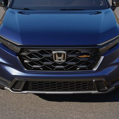 2027 Honda CR-V TrailSport Hybrid in Canyon River Blue Metallic front parked on a paved road outdoors (Compact Crossover SUV).